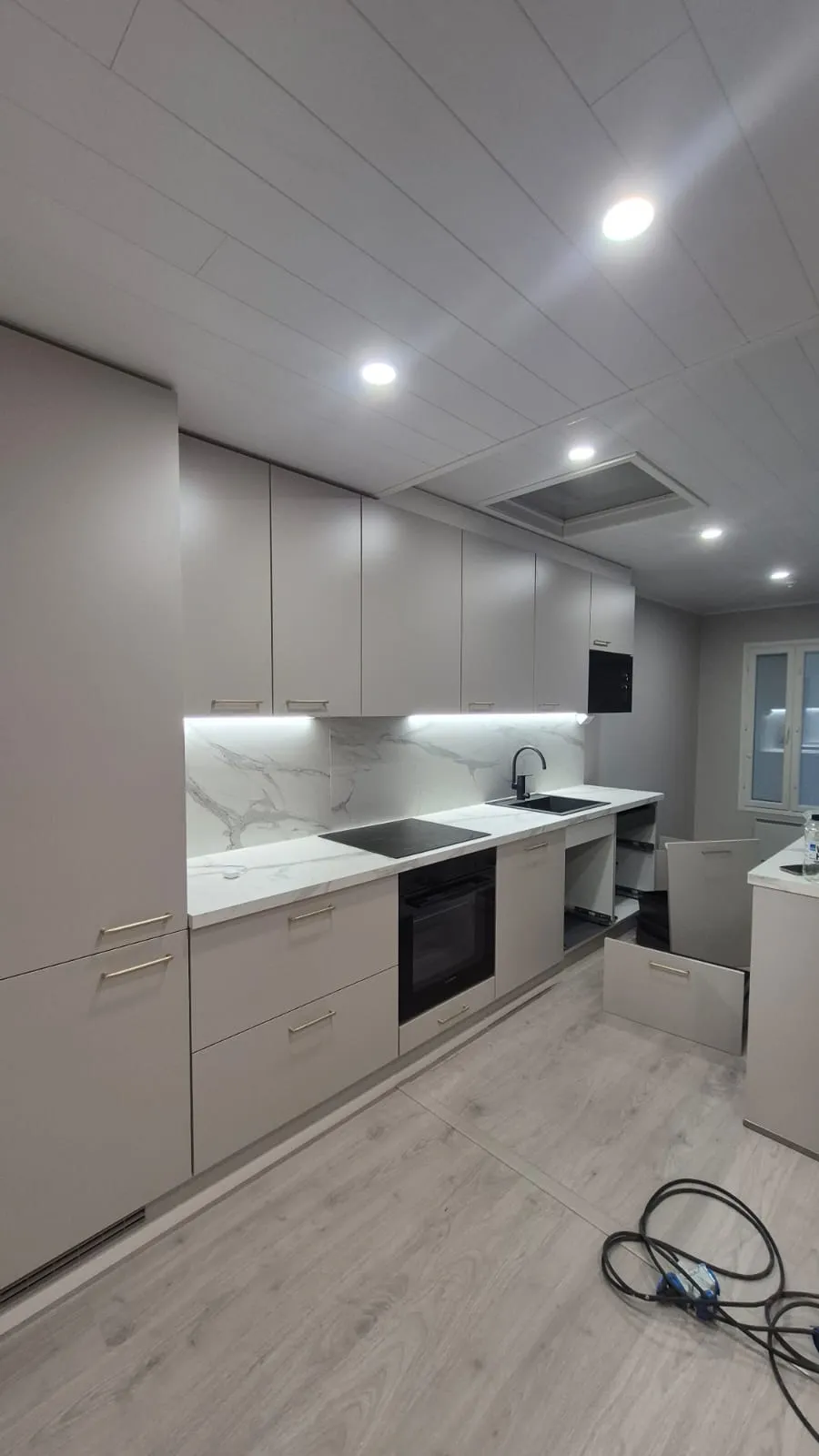 Vaaleanharmaa keittiö, marmorinen tausta, moderni valaistus.